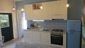 A kitchen with white cabinets, a blue refrigerator, and a gas stove. - Il Veliero Appartamento  con Giardino (Terracina)