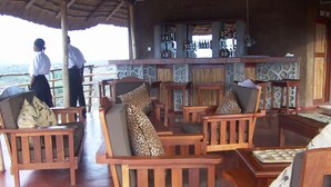 Uma área de bar com cadeiras de madeira e parede de pedra.