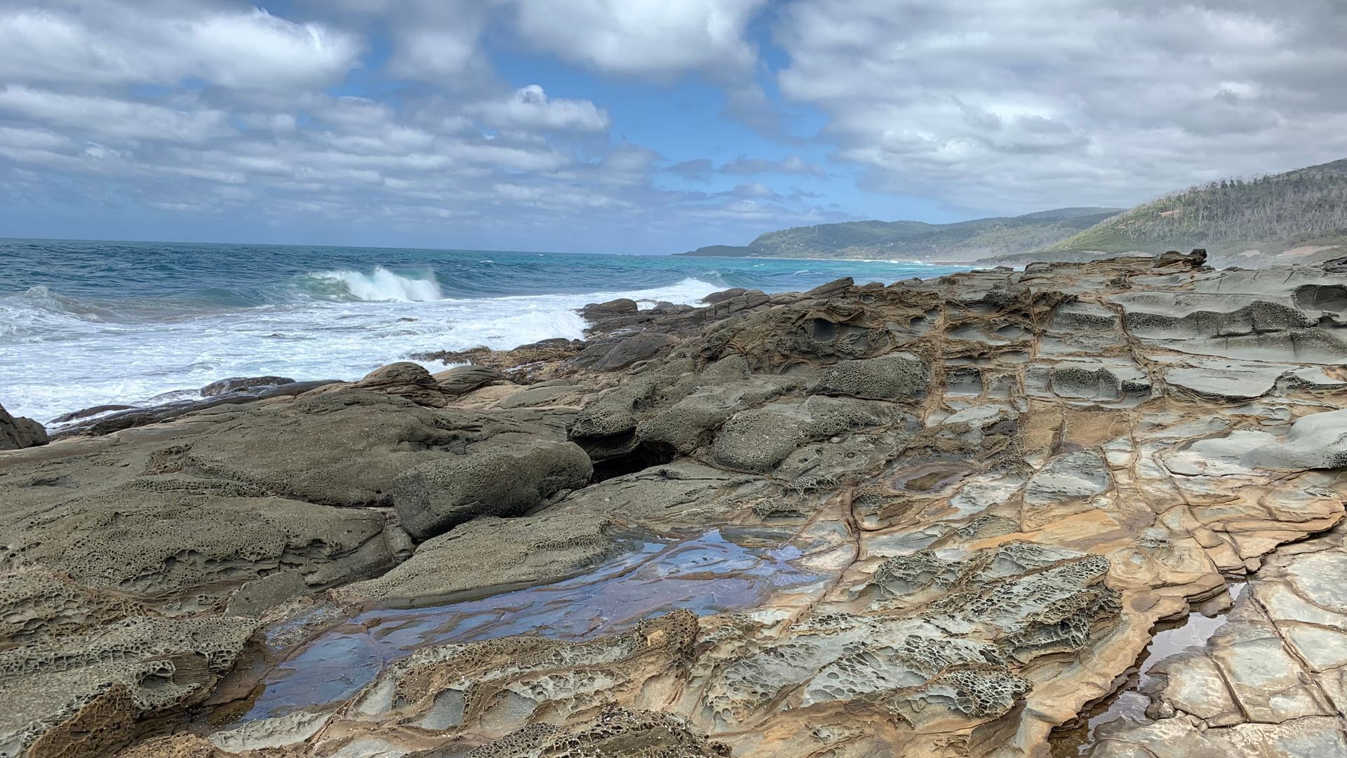 A rocky coastal landscape with waves crashing against the shore.