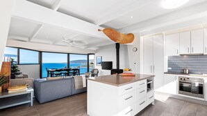 A modern kitchen with white cabinetry, a central island, and a view of the ocean.