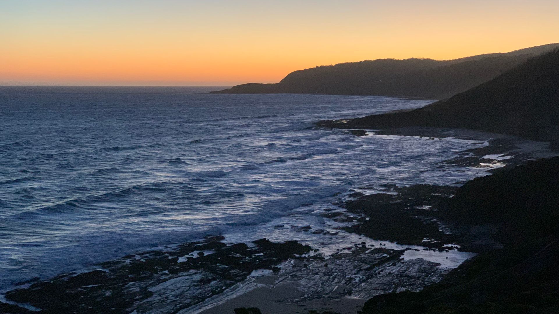 A coastal landscape with a rocky shoreline and a view of the ocean.