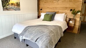 A bedroom with a bed, a painting, an air conditioner, and a nightstand with a vase. - Peaceful & Picturesque Farm Stay Only 5 Mins Drive From Benalla Township (Benalla)