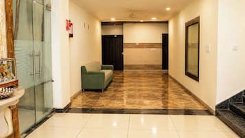A hotel lobby with a green sofa, a reception desk, and a fire extinguisher.