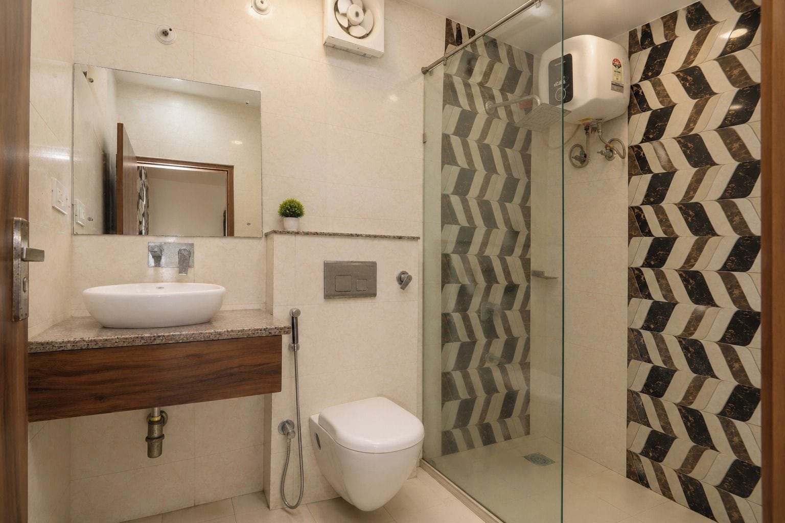 Un baño moderno con ducha envuelta en vidrio, un lavamanos blanco y un inodoro.