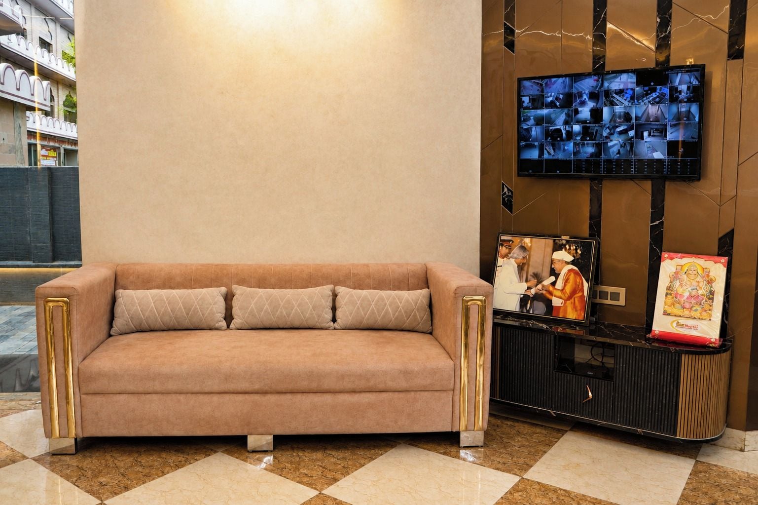 Un vestíbulo moderno con un sofá color crema, un televisor de pared y un objeto decorativo.