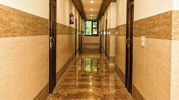 Un pasillo de hotel con piso de mármol, techo de madera y puertas a ambos lados.