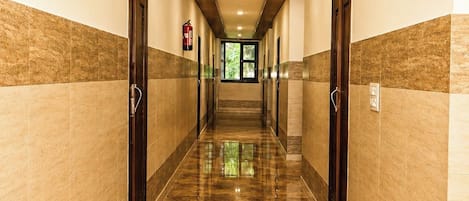 Un pasillo de hotel con piso de mármol, techo de madera y puertas a ambos lados.