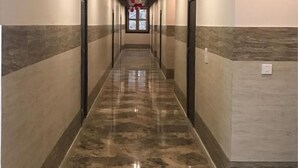 A long, narrow hallway with a polished marble floor and a series of doors on both sides. - Hotel YashoGopal Resortico (Mathura)