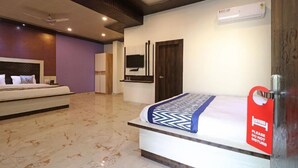 Quarto de hotel com cama, televisão, ar condicionado e uma placa vermelha na porta.