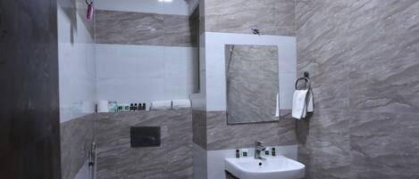 A bathroom with a toilet, sink, and shower area.