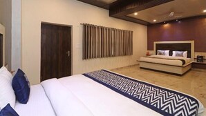 A modern hotel room with a large bed, a bedside table, a headboard, and a ceiling fan. - Hotel YashoGopal Resortico (Mathura)