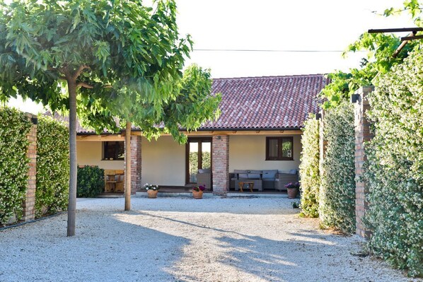 A house with a tiled roof, a covered patio, and a gravel driveway.
