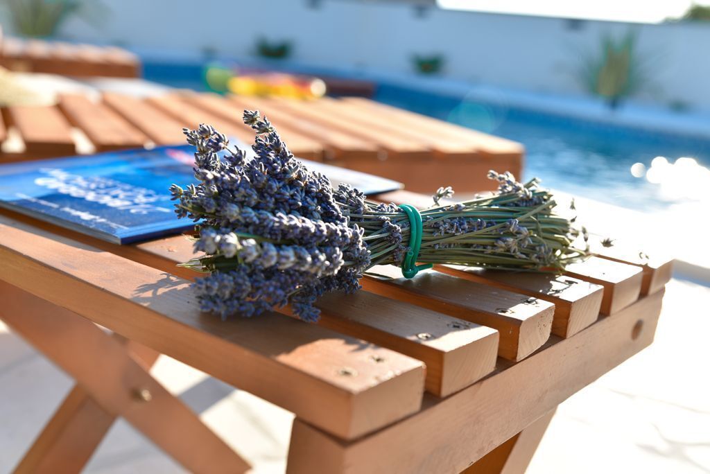 Une table en bois, sur laquelle est posé un bouquet de lavande et un livre à la couverture bleue.