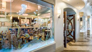 A restaurant with a large glass window displaying an underwater scene. Inside, there are tables and chairs arranged for dining. - "Enchanted Escape" - Game Room|Massage Chairs|Peloton Bike|Sleeps 23 (Davenport)