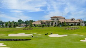 A golf course with sand bunkers, a clubhouse, and a large building in the background. - "Enchanted Escape" - Game Room|Massage Chairs|Peloton Bike|Sleeps 23 (Davenport)