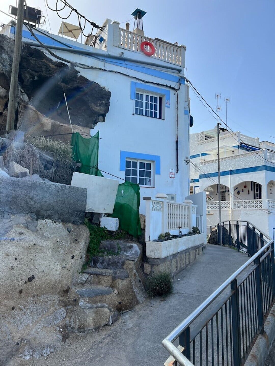 A white building with blue trim and a red lifebuoy on the roof.