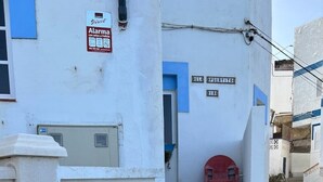 A narrow street with a white building, a red chair, and a sign indicating an alarm system. - Claudia Puertito de Adeje - 1 bedroom, 70sqm, on the beach (CN)