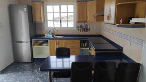 A compact kitchen with wooden cabinets, a stainless steel refrigerator, a sink, and a window providing a view. - Claudia Puertito de Adeje - 1 bedroom, 70sqm, on the beach (CN)