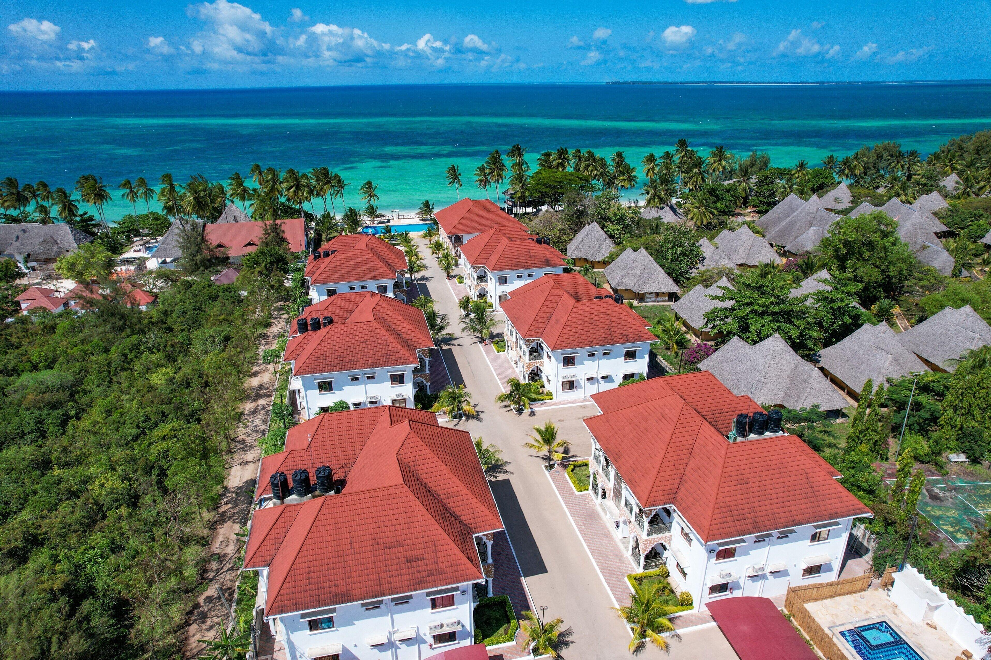 A resort with multiple buildings, a swimming pool, and a view of the ocean.