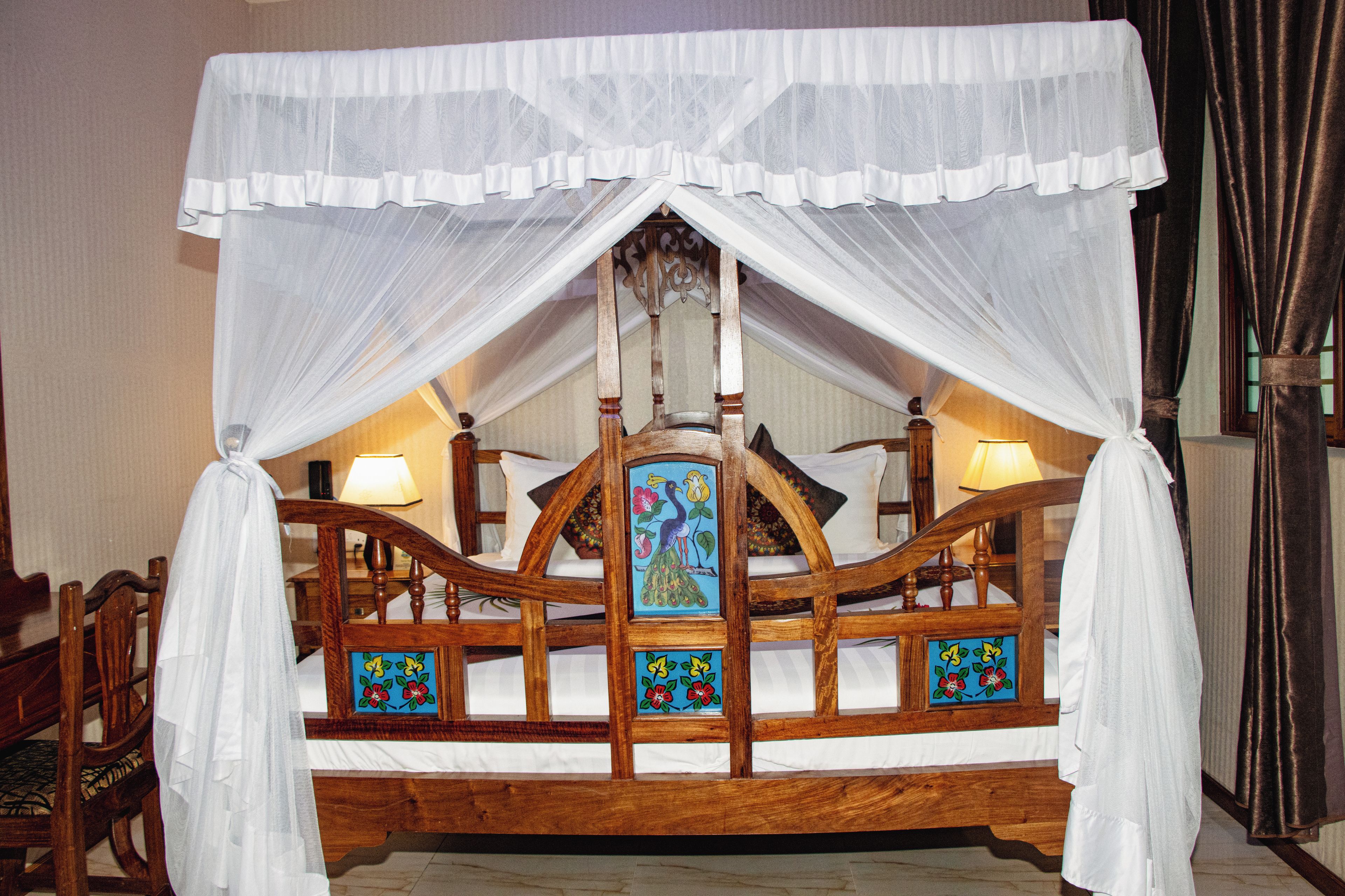 A bed with a canopy, wooden headboard, and floral-patterned pillows.