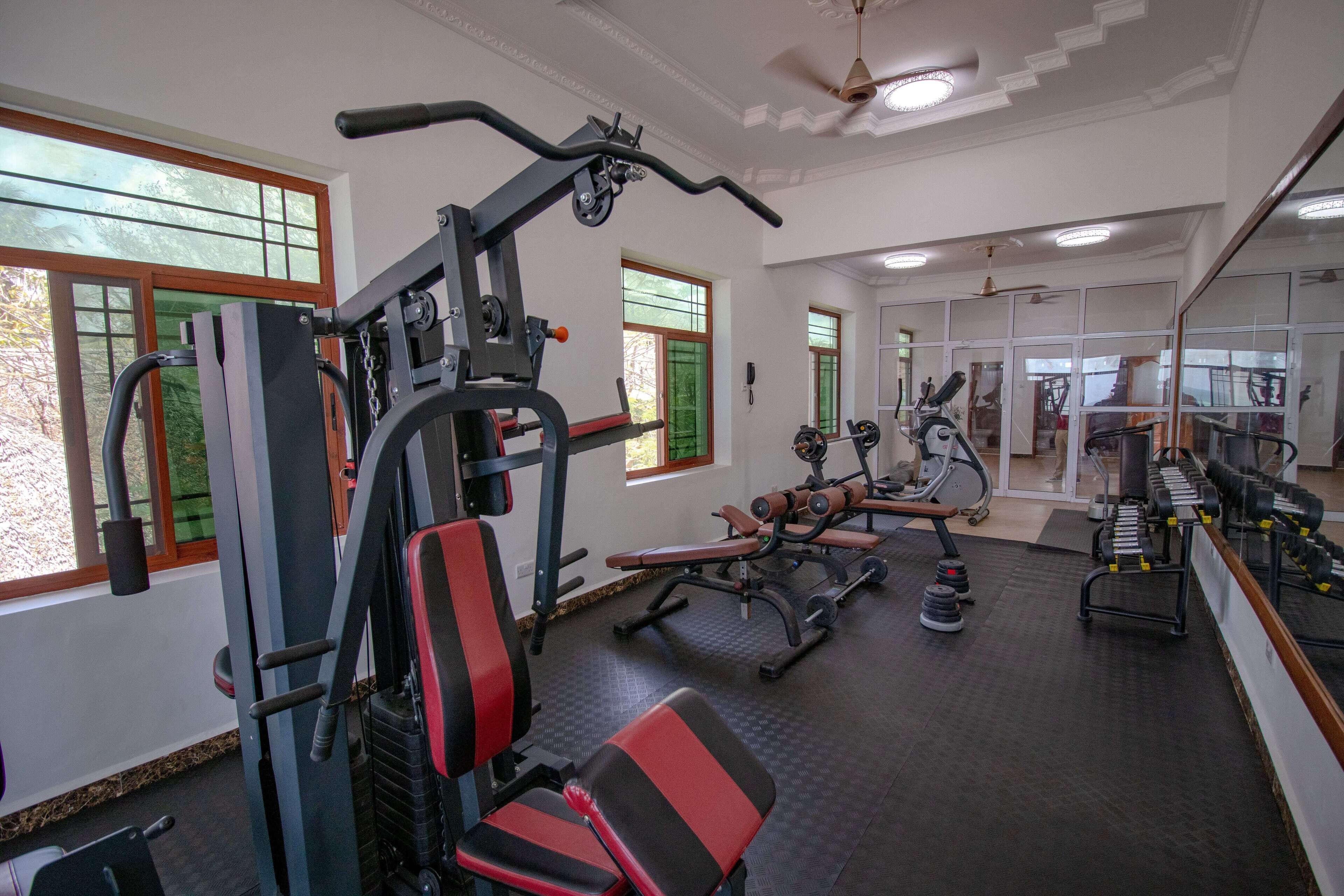 Ett gym med träningsredskap, bänkar och en spegel.