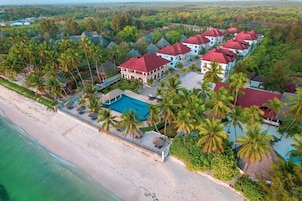 An aerial view of a resort with multiple buildings, a swimming pool, and a beach.