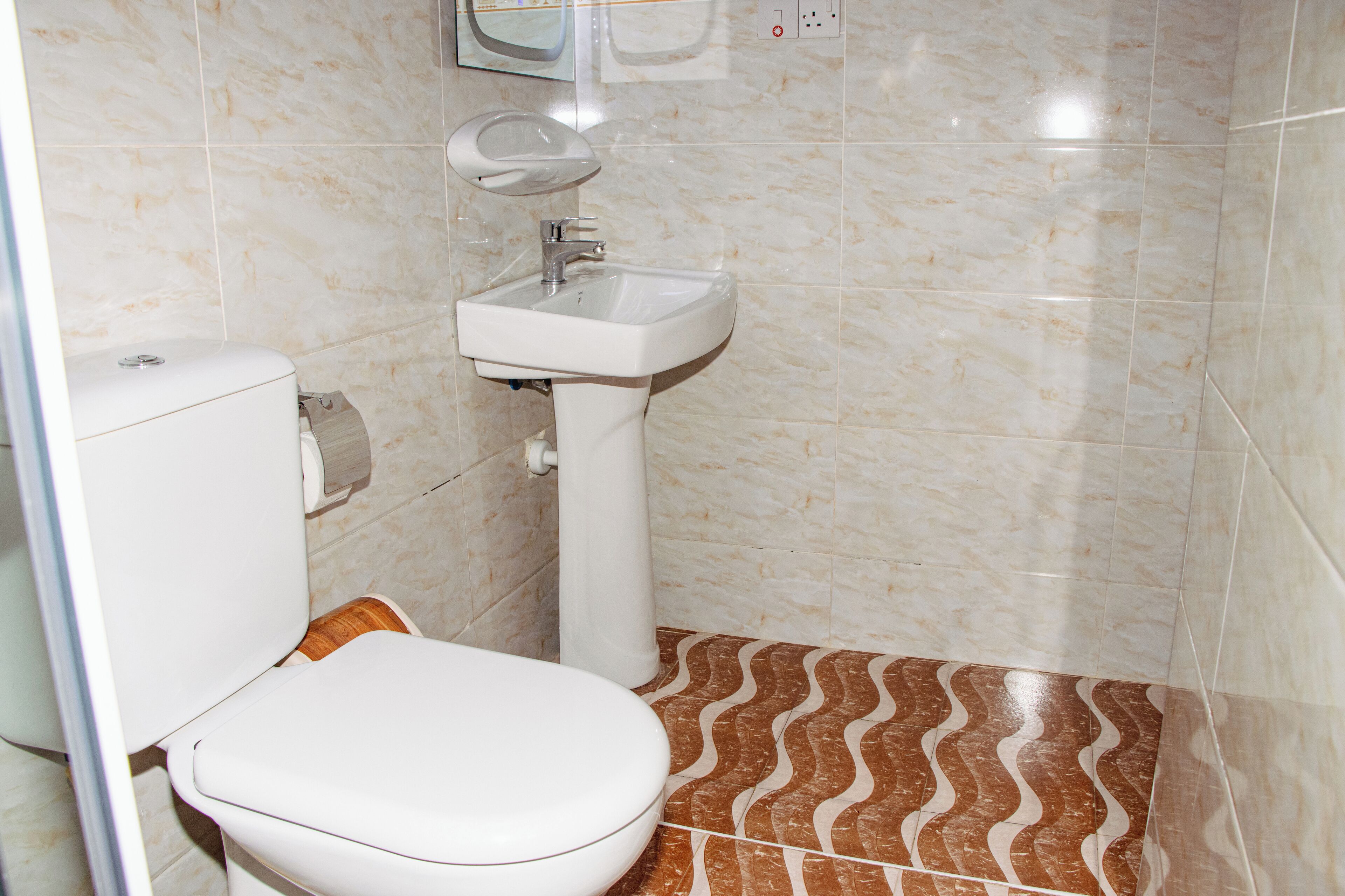 Une salle de bain avec des toilettes, un lavabo et des carreaux de sol à motifs.
