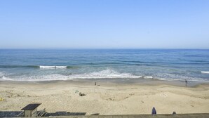 A beach with a lifeguard tower, clear skies, and calm sea. - Luxury Beachfront Villa - Penthouse B (Carlsbad)