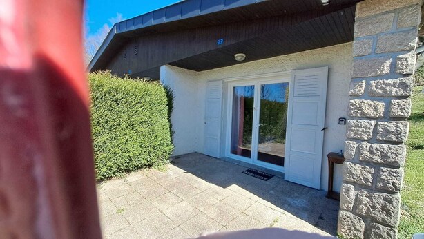 A house with a stone exterior, a tiled patio, and a sliding glass door. - Le Paradis de Marie (Treignac)