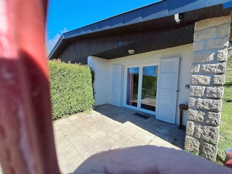 A house with a stone exterior, a tiled patio, and a sliding glass door.