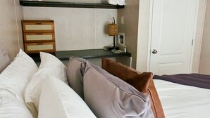 A hotel room with a bed, pillows, a nightstand, a lamp, and a door. - Private, detached 1 bedroom apt. 6 miles from Folly Beach & downtown Charleston (Charleston)