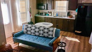A compact living space with a blue sofa, a small round table, and a kitchen area with a microwave and refrigerator. - Private, detached 1 bedroom apt. 6 miles from Folly Beach & downtown Charleston (Charleston)