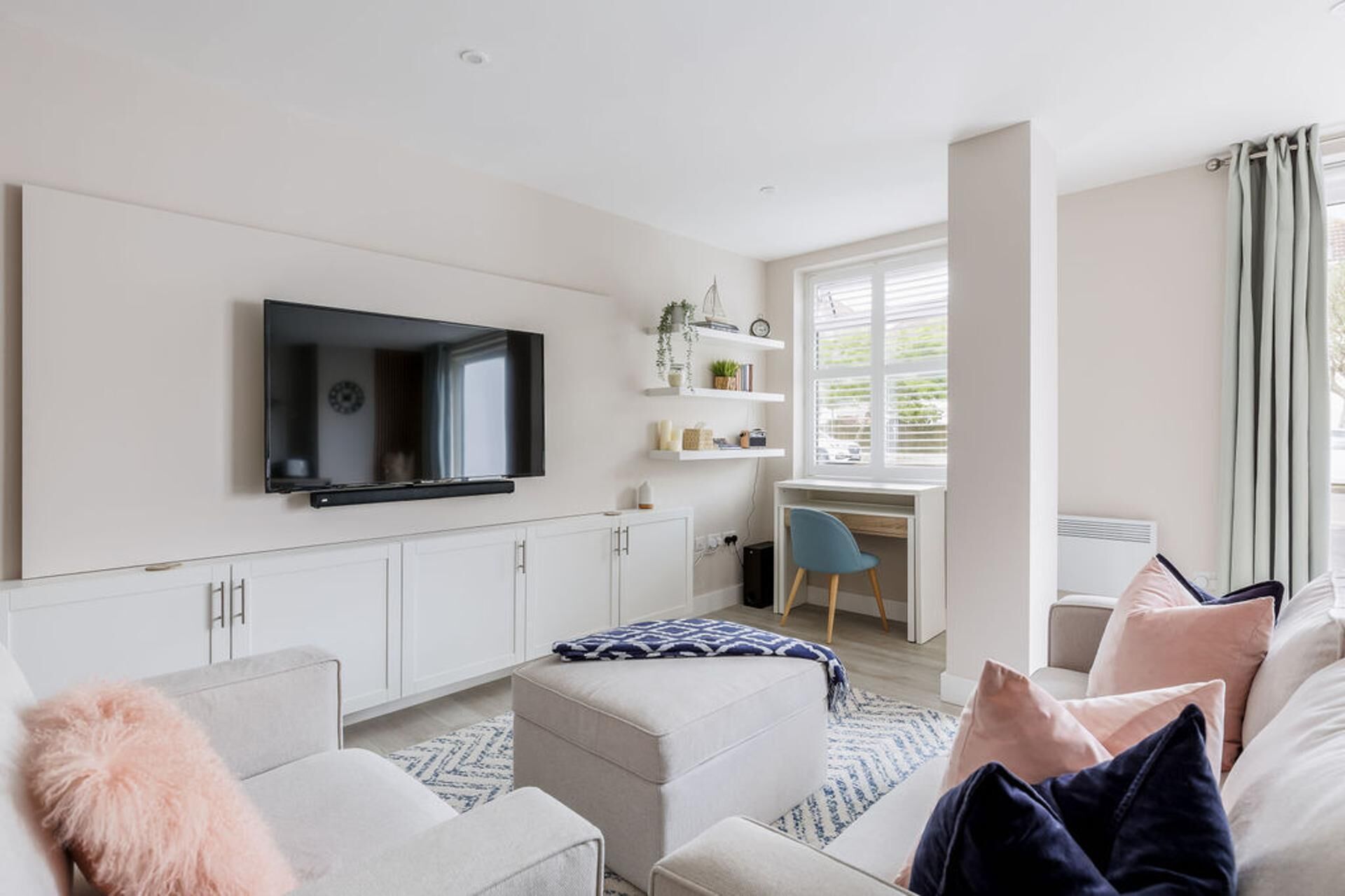 Een moderne woonkamer met een flatscreen televisie, een bureau en een comfortabele zithoek.