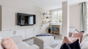 A modern living room with a flat-screen TV, a desk, and a comfortable seating area. - Modern 2bed Flat, Parking, Close to Beach & Shops (Bournemouth)