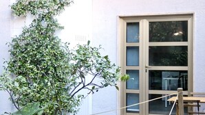 A building with a large window, a potted plant, and a wooden table. - BuenRetiroPe_Ita - Comfortable two-room apartments with garden (Pescara)
