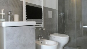 A modern bathroom with a glass-enclosed shower, a white sink, and two bidets. - BuenRetiroPe_Ita - Comfortable two-room apartments with garden (Pescara)
