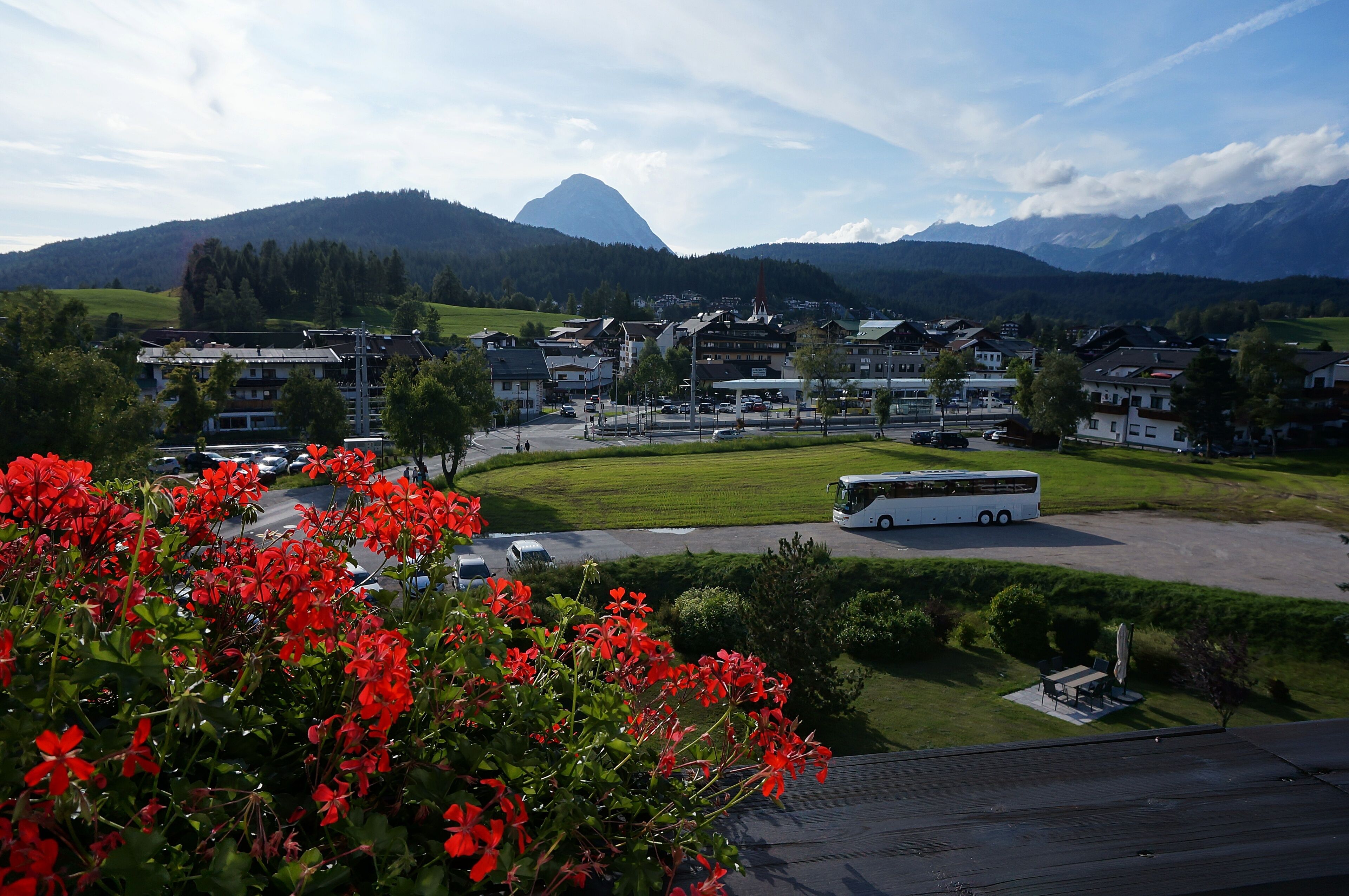 A town with a bus station, buildings, and mountains in the background.