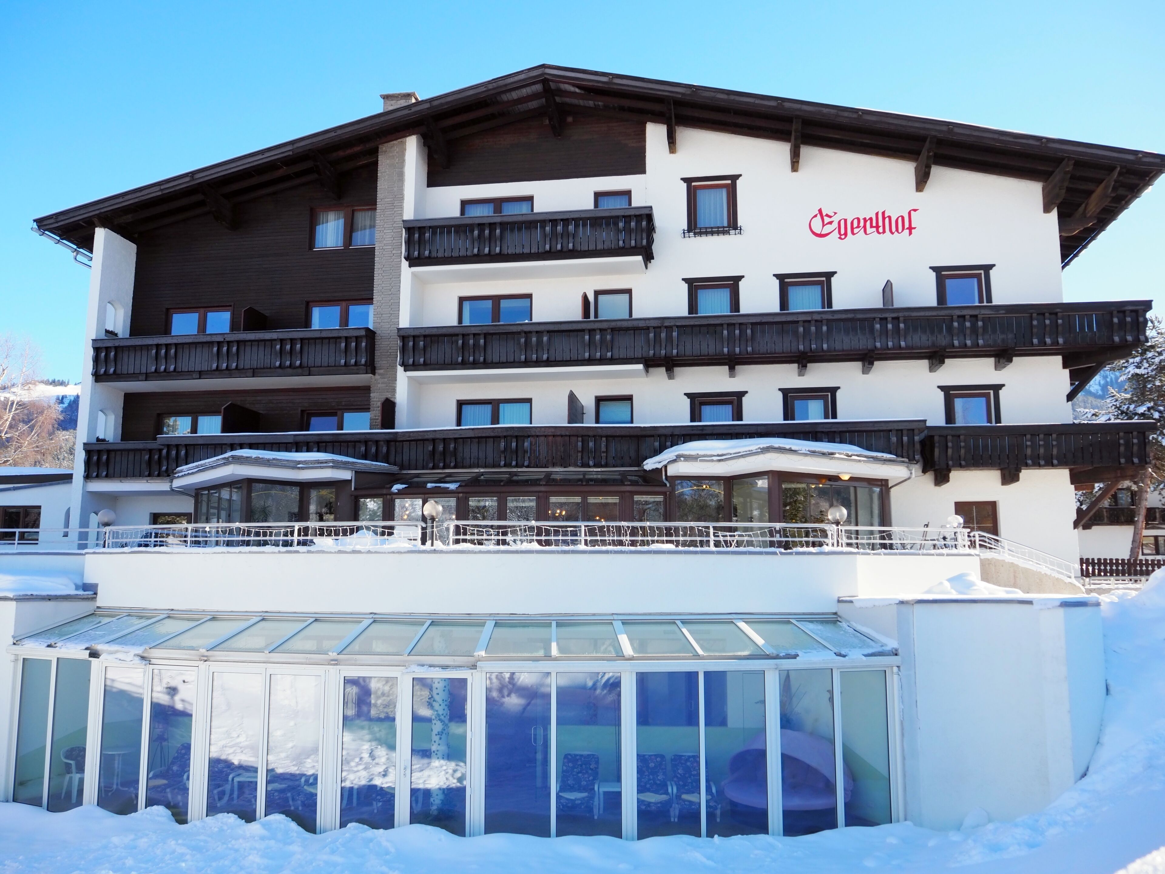 A multi-story hotel with balconies, a glass conservatory, and a sign reading "Egenhof".