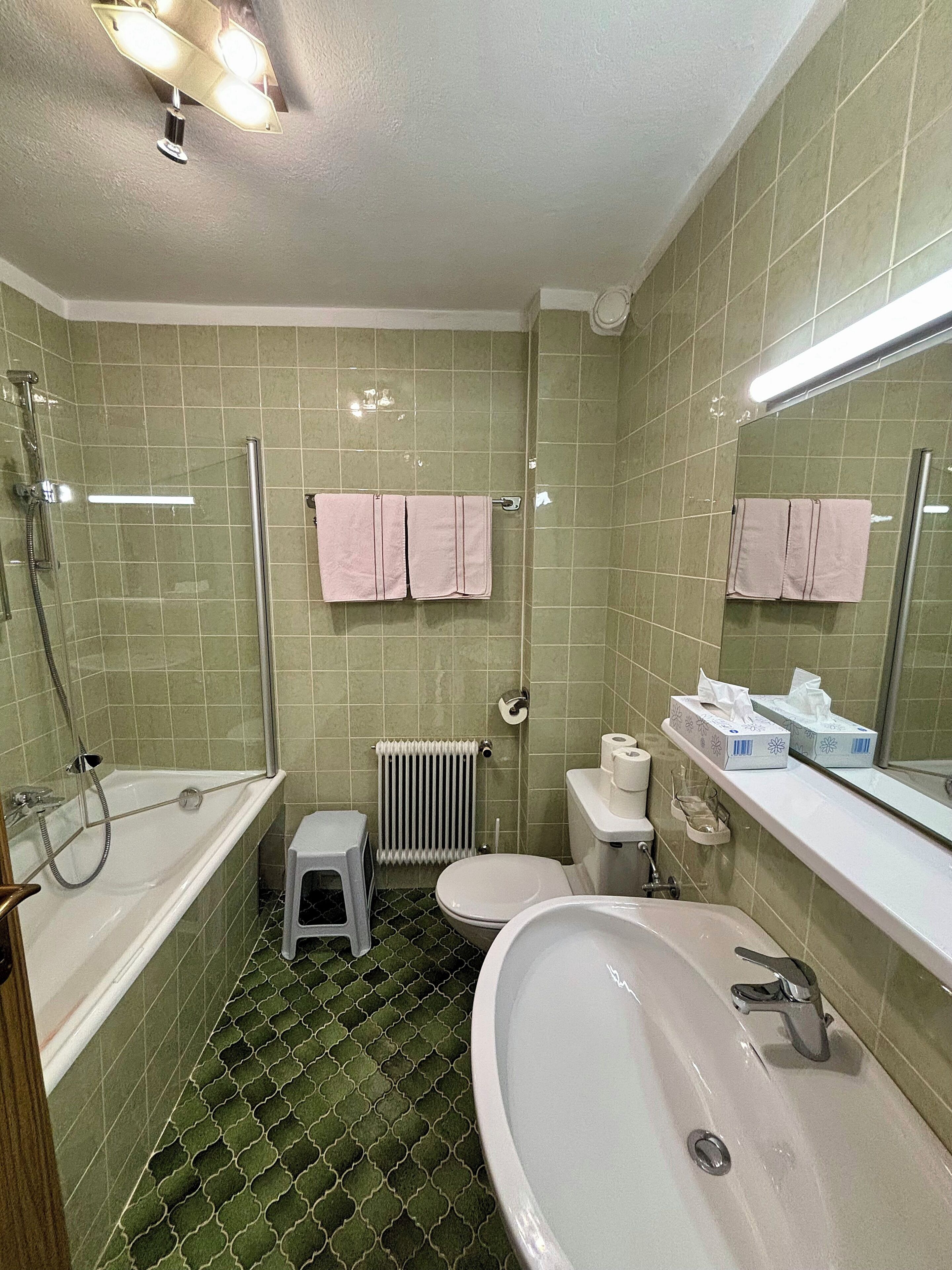 A bathroom with a bathtub, toilet, and sink. There are two pink towels hanging on the wall.