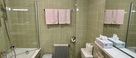 Un baño con bañera, inodoro y lavamanos. Hay dos toallas rosas colgadas en la pared.