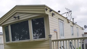 Ein Wohnmobil mit eingezäunter Terrasse, Satellitenschüssel und Schornstein.