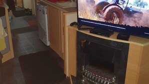 Eine kompakte Küche mit integriertem Fernseher, einem kleinen Kühlschrank und einer Mikrowelle.