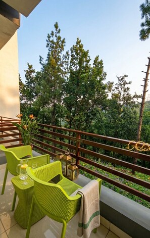 A balcony with green chairs, a table, and a view of trees. - Pine Valley Gold Resort (Lansdowne)