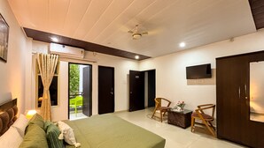 Habitación de hotel con cama, televisor en la pared, ventilador de techo y ventana con cortinas.