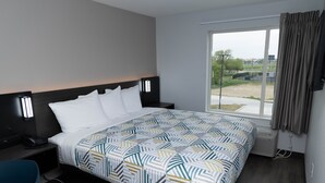 A modern hotel room with a large bed, bedside tables, a desk, and a window with curtains. - Motel 6 Fort Worth, TX - Lake Worth (Fort Worth)