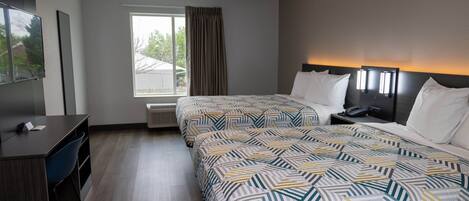 A hotel room with two beds, a desk, a chair, and a large window with curtains.