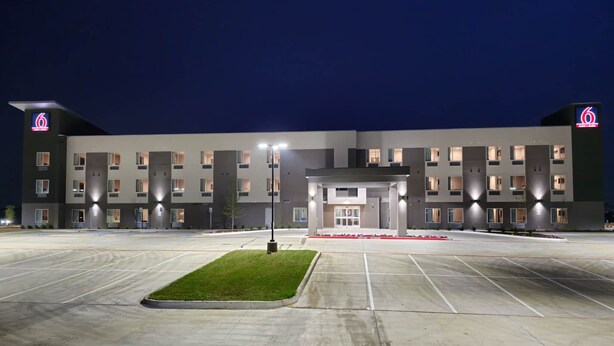 A modern hotel with a central entrance, multiple floors, and a parking lot. - Motel 6 Fort Worth, TX - Lake Worth (Fort Worth)
