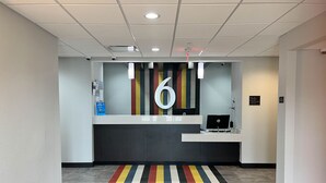 A reception area with a modern design, a reception desk, a digital display, and a colorful striped carpet. - Motel 6 Fort Worth, TX - Lake Worth (Fort Worth)