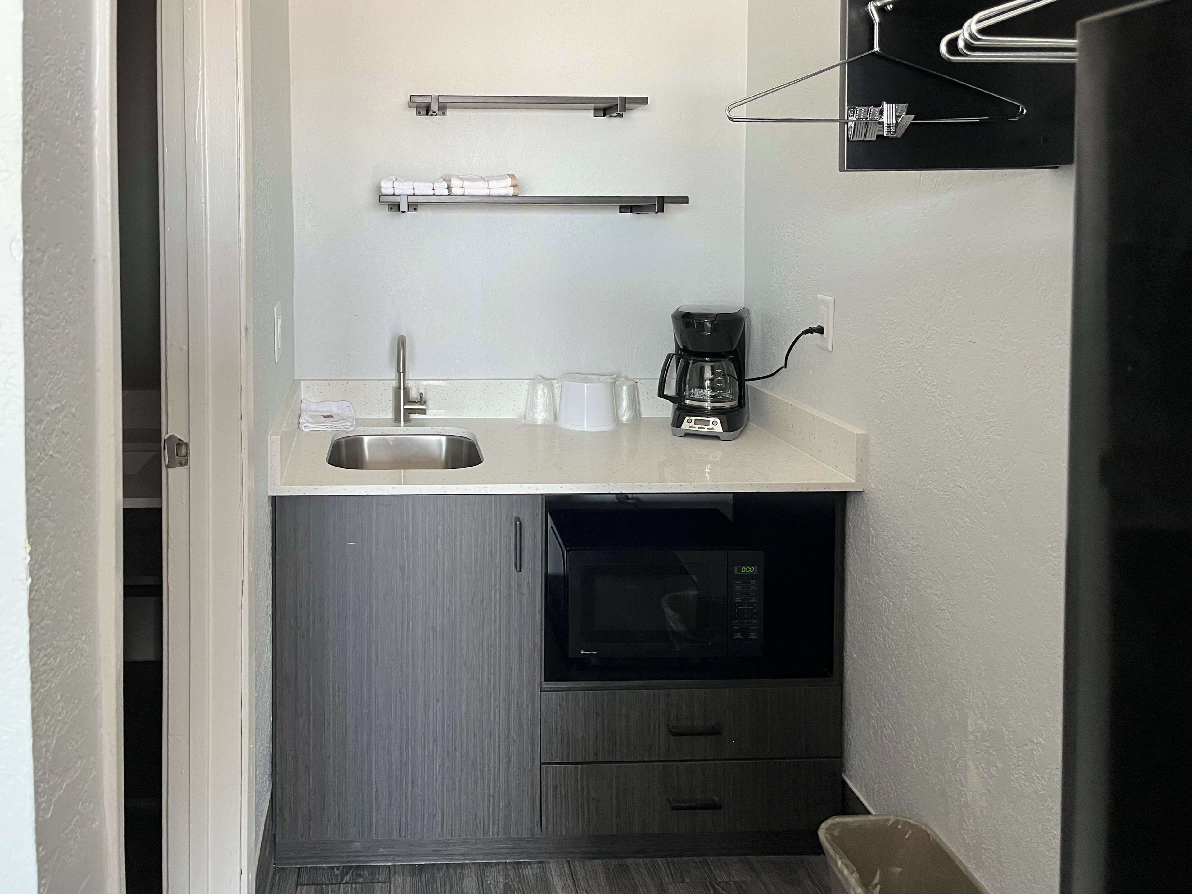 A compact kitchenette with a sink, a coffee maker, and a microwave.