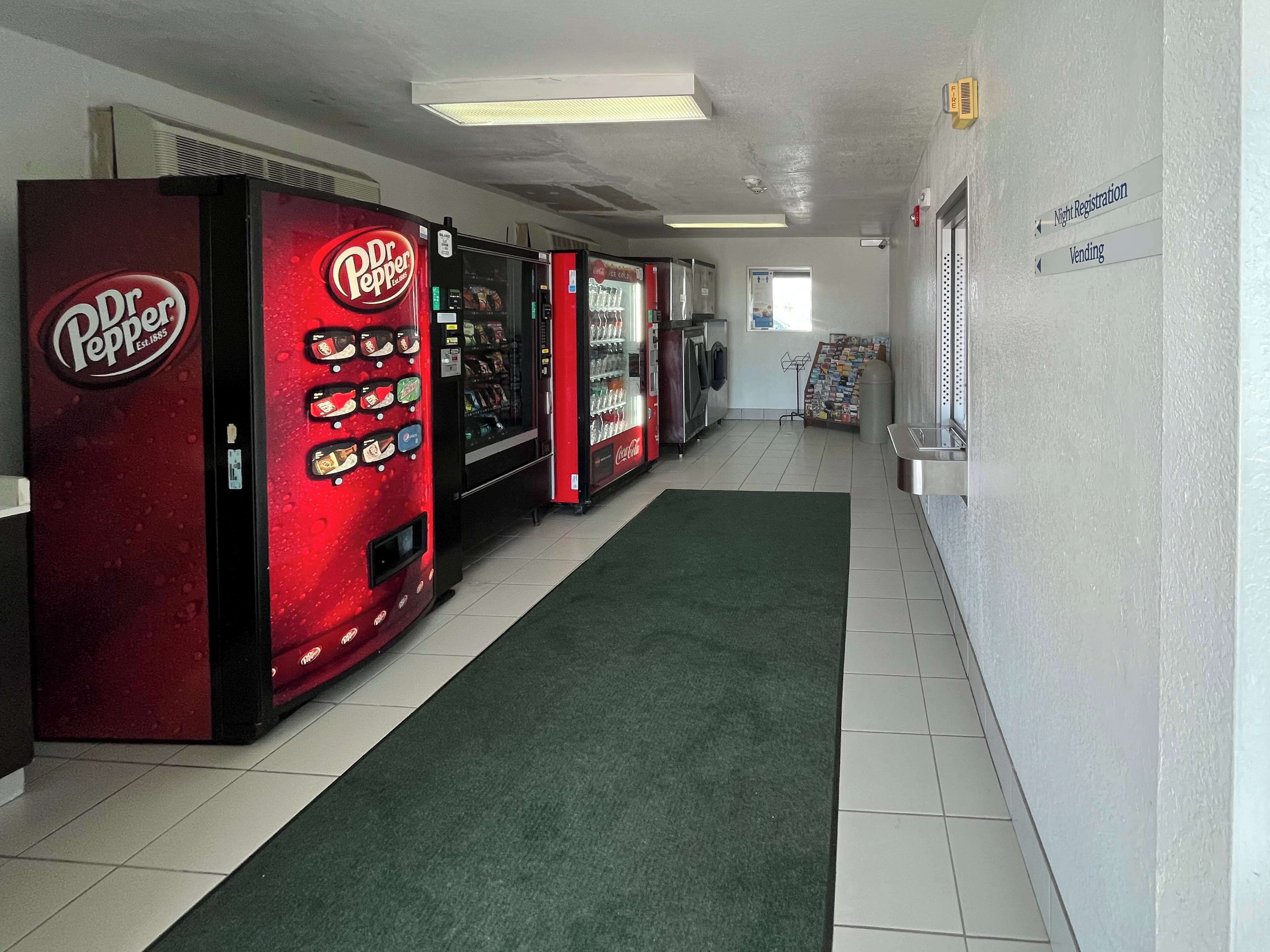 A hallway with vending machines, including Dr. Pepper and Coca-Cola, and signs for night registration and vending.